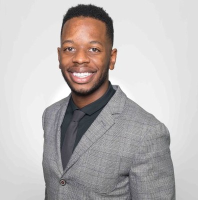 Kyle James smiling in a gray plaid suit